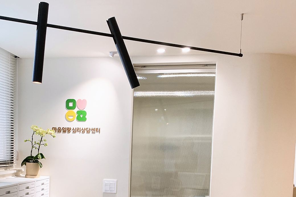 마음일랑 심리상담센터 로고가 붙은 벽과 검은 조명, 난 화분